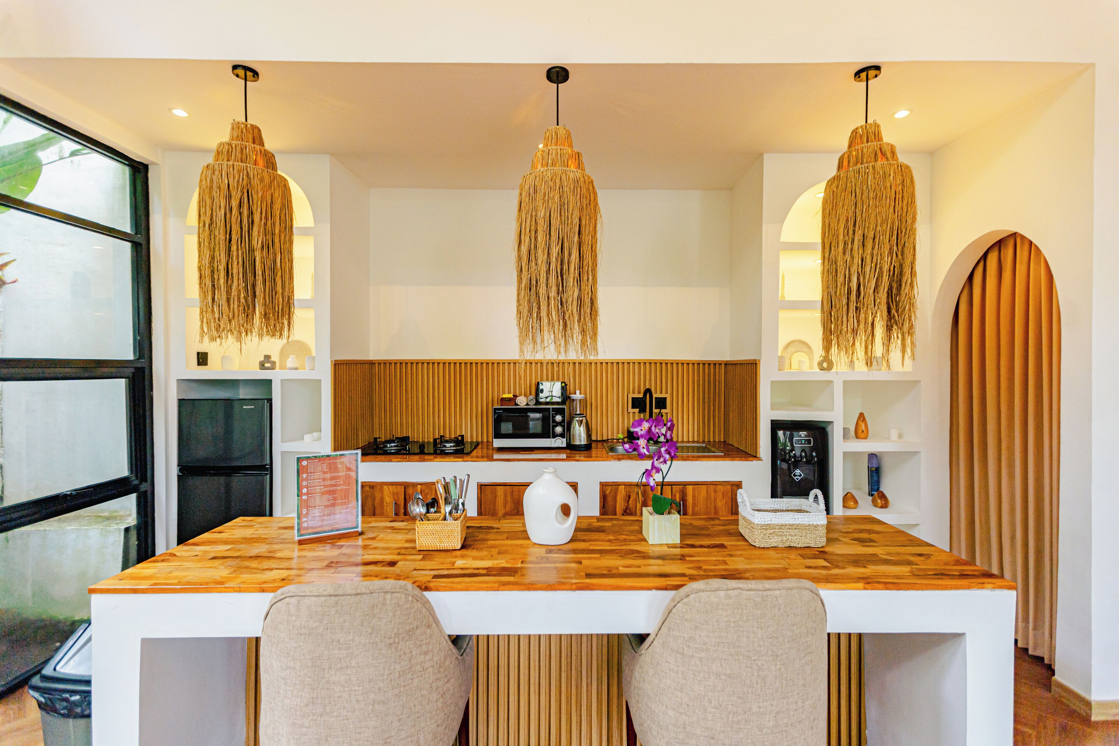 A modern kitchen with wooden countertops, a central island, and hanging pendant lights.