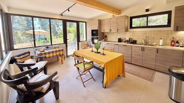 Una cocina moderna con ventanas amplias, un comedor con mesa y sillas, y vistas al exterior.