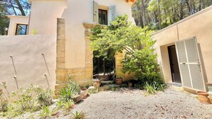 Una casa con fachada de piedra, camino de grava y jardín con diversas plantas.