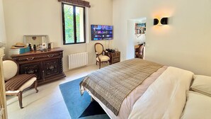 Un dormitorio con cama, cómoda, silla y televisor en la pared.