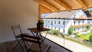 Ein Balkon mit Holzmöbeln, einem Blumentopf und Blick auf Gebäude.