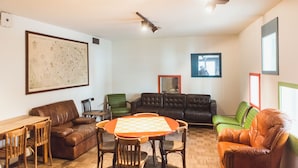 Una habitación con un mapa grande en la pared, una mesa de ajedrez, sofás de cuero y un ventilador de techo.