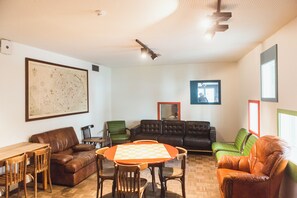 Una habitación con un mapa grande en la pared, una mesa de ajedrez, sofás de cuero y un ventilador de techo.