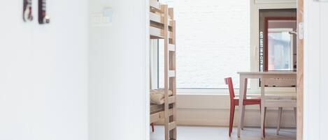 A room with a bunk bed, a desk, and a chair.