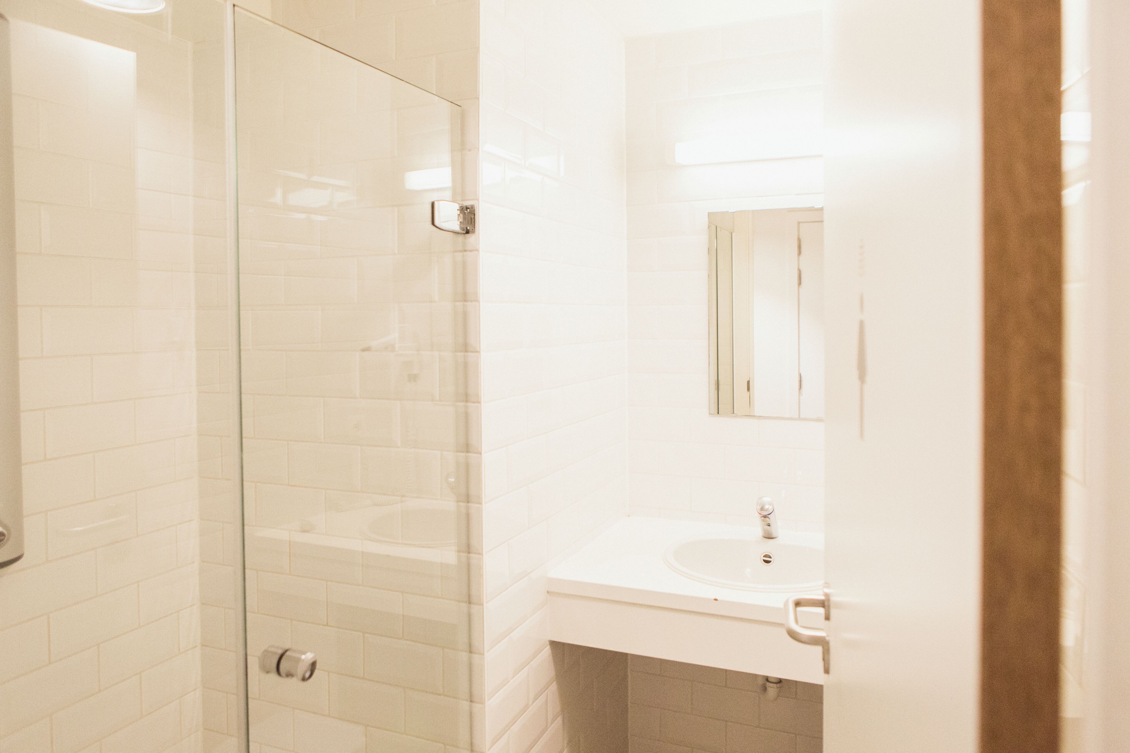 A bathroom with a glass shower enclosure, a sink, and a mirror.