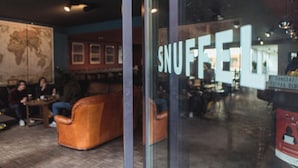 Un interior acogedor con un mapa grande en la pared, una zona de estar con sofás de cuero y un cartel que dice 'SNUFFEL'.