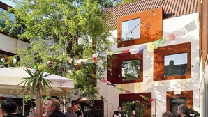 Un espacio al aire libre con mesas y bancos, rodeado de edificios con grandes ventanales y tejado de tejas.