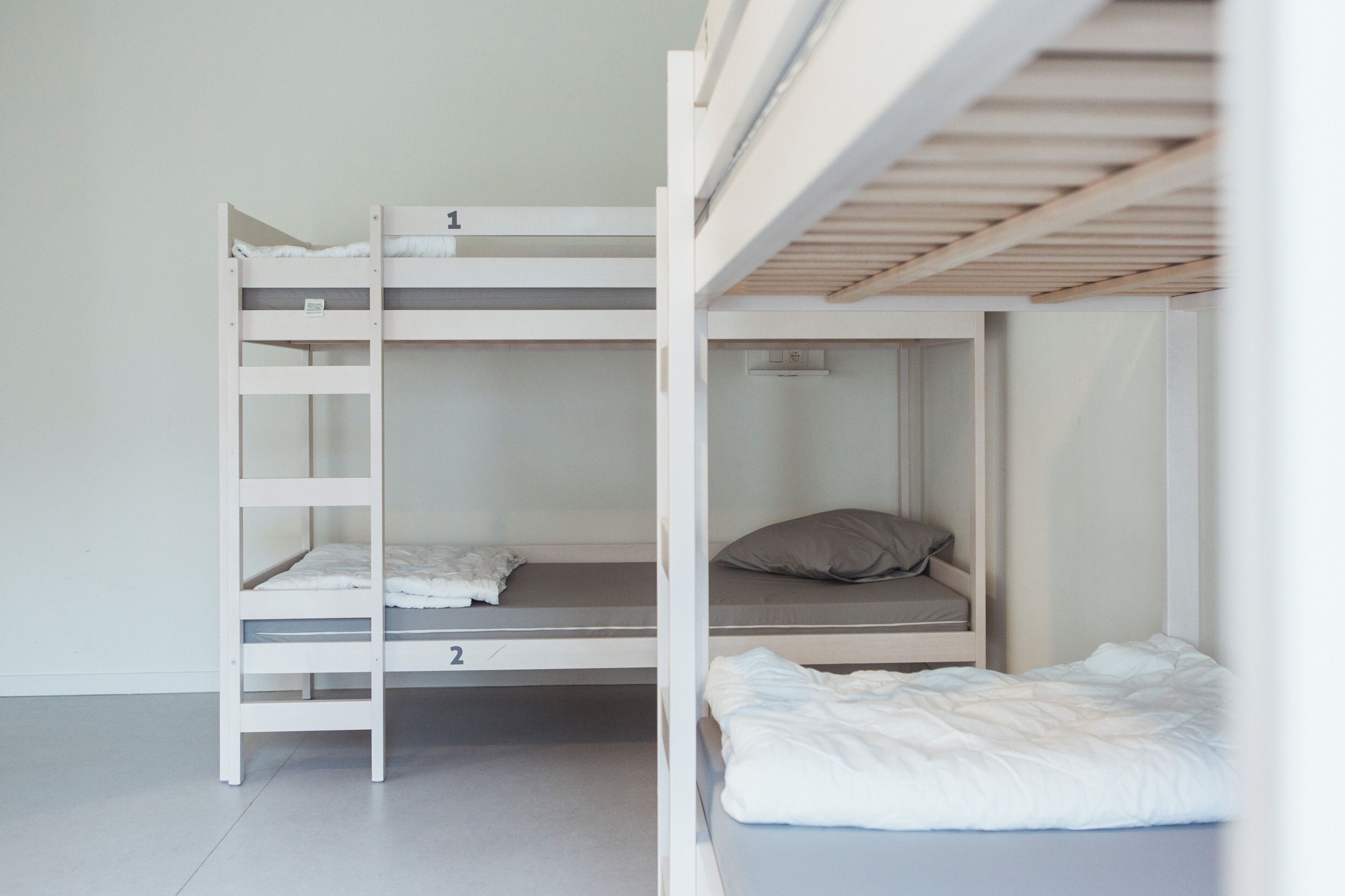 Een stapelbed met twee niveaus, een klein plankje en een enkel bed met een kussen.
