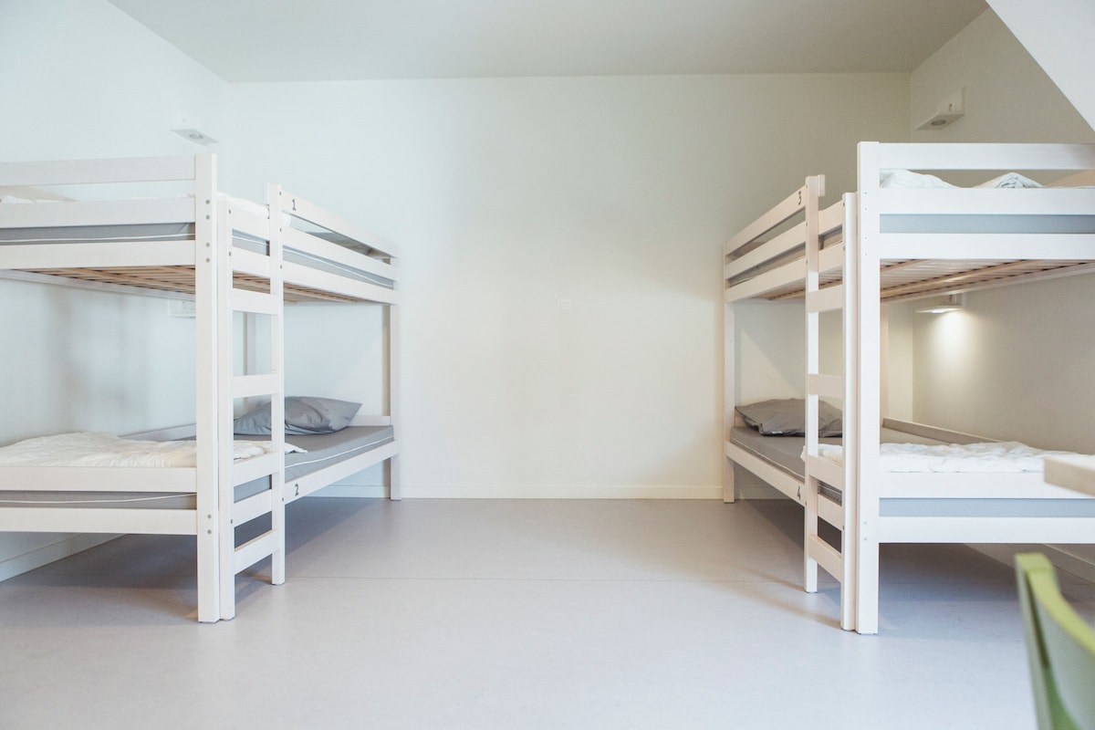 Una habitación con dos literas, cada una con colchón y almohadas.