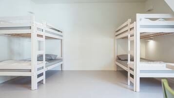 Ein Zimmer mit zwei Etagenbetten, jeweils mit einer Matratze und Kissen.