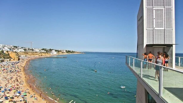 Une plage avec un bâtiment doté d’un balcon donnant sur la mer.