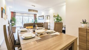 Un espace repas moderne avec une table en bois dressée pour quatre personnes, un canapé et une grande fenêtre.