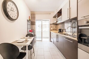 A modern kitchen with a dining area, a clock on the wall, and a view through the glass door. - Verasol N, 5 minutes from Praia dos Pescadores, Albufeira (Albufeira)