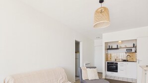 A modern living room with a sofa, a chair, and a kitchen area with appliances. - Breathtaking ocean view, stay for 2 (Saint-Gilles-Croix-de-Vie)