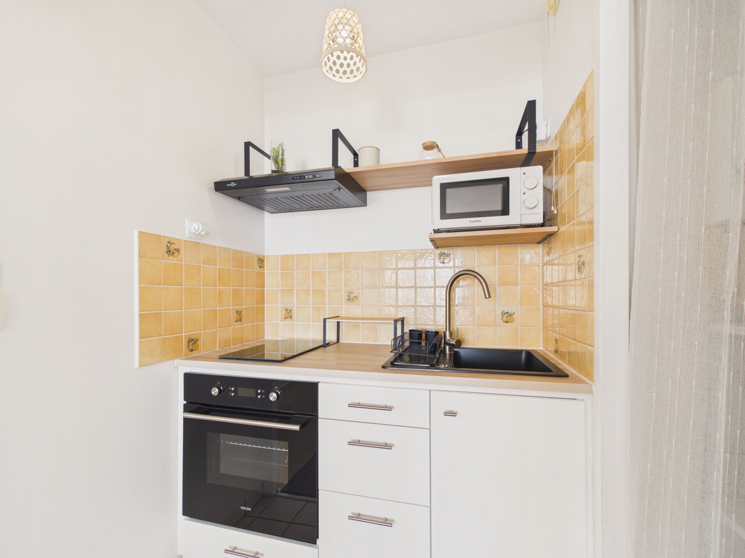 A kitchen with a black oven, a microwave, and a sink with a faucet.