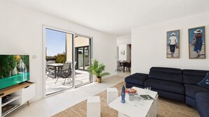 Ein modernes Wohnzimmer mit Fernseher, Sofa, Couchtisch und Kunstwerken.