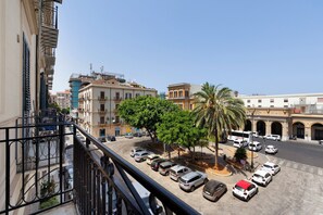 A street view with parked cars, a palm tree, and buildings with balconies. - Room 'Binario' with Balcony, Wi-Fi and Air Conditioning (Palermo)