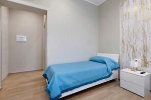 Ein Schlafzimmer mit einem Einzelbett, einem Nachttisch, einer Lampe und einer Wand mit einer strukturierten Oberfläche.