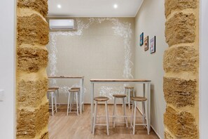 Ein Zimmer mit Backsteinwand, Klimaanlage und einem Holztisch mit vier Hockern.