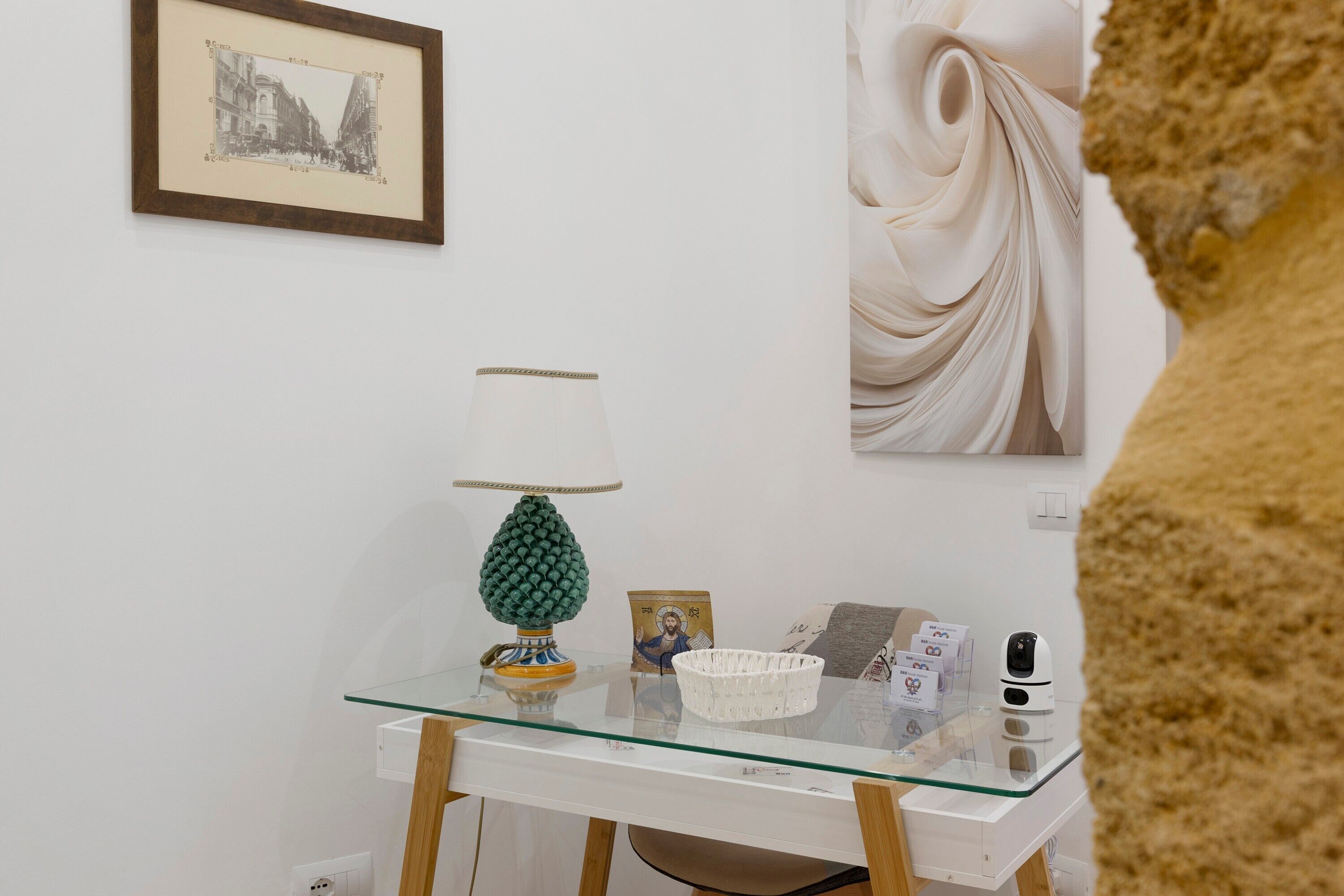 Una habitación con una mesa de vidrio que muestra una lámpara, una cesta y un cuadro enmarcado.
