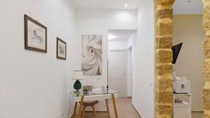 Un pasillo con una mesa de vidrio, cuadros enmarcados y una pared con textura.