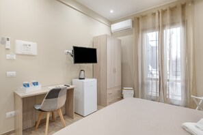A hotel room with a bed, a desk with a chair, a television, a wardrobe, and a window with curtains. - Room 'Ferrovia' with Balcony, Wi-Fi and Air Conditioning (Palermo)