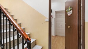 Una escalera de madera con barandilla, una puerta con un letrero y un interruptor de luz en la pared.