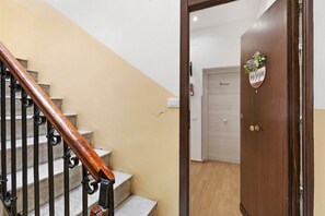 A wooden staircase with a handrail, a door with a sign, and a light switch on the wall. - Room 'Ferrovia' with Balcony, Wi-Fi and Air Conditioning (Palermo)