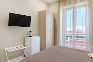 Ein Hotelzimmer mit Bett, Wandfernseher, Kleiderschrank, einer kleinen Küchenzeile und einem Balkon mit Blick.