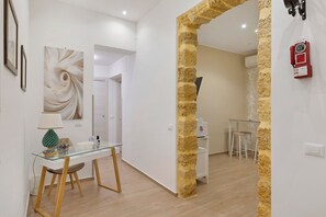 Een modern interieur met een glazen eettafel, een houten stoel, een wand met een structuurkolom, en een rode telefoon.
