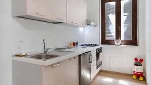 A kitchen with a stainless steel sink, a gas stove, and a window with blinds. - Room 'Stazione' with Balcony, Wi-Fi and Air Conditioning (Palermo)
