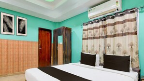 Una camera d'albergo con un letto, un condizionatore, una porta e una parete decorata con due quadri.