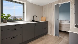 A modern kitchen with a large window, a sink, and a view of the city. - Top apartment in Henningsvær (Vågan)
