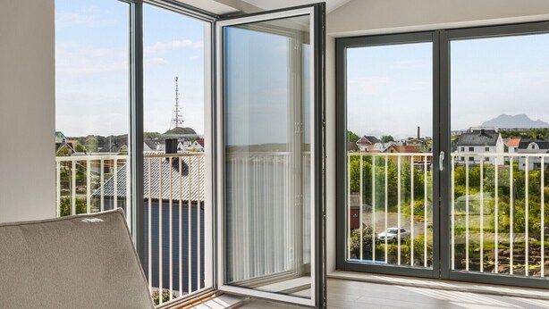 A balcony with a sofa and a table with a vase and a candle. - Top apartment in Henningsvær (Vågan)