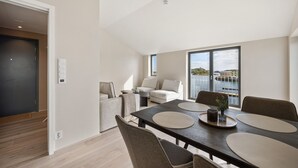A modern living room with a dining area, large windows, and a view of the water. - Top apartment in Henningsvær (Vågan)