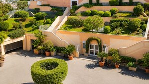 A multi-story hotel with a landscaped garden, a central staircase, and a pool area. - Panoramic sea view • Swimming pool • Terrace • Tennis court • Parking • Cannes (Cannes)