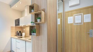 Eine moderne Küche mit eingebauten Geräten, Holzregalen mit Pflanzen und einer Holztür mit Aushängen.