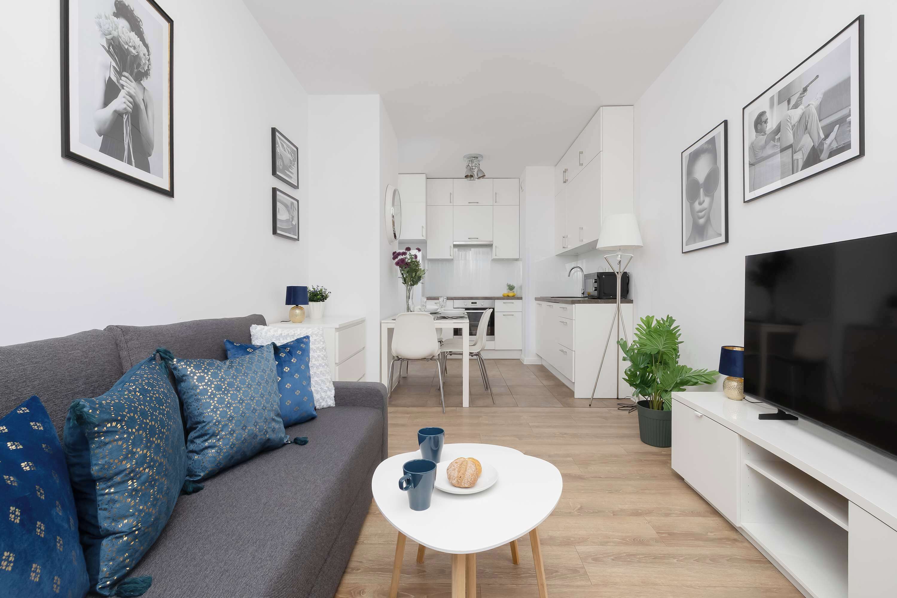 A modern living room with a grey sofa, a white coffee table, and a flat-screen TV.