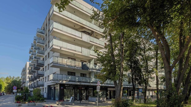 Un edificio de varios pisos con balcones, una entrada cubierta y un letrero que indica zona sin estacionamiento.