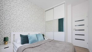 Un dormitorio con cama, mesita de noche, cómoda y puerta corredera al armario.