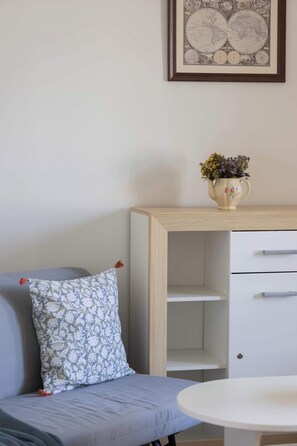 A room with a sofa, a small table, a cabinet, and a framed map on the wall. - Spacious Apartment for 6 Guests with a Bathtub in Warsaw by Noclegi Renters (Warszawa)
