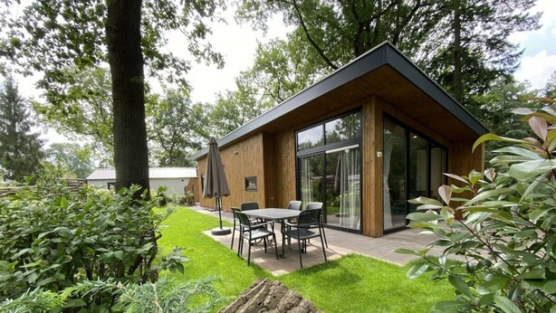 Een modern huis met een terras, een eettafel en stoelen.