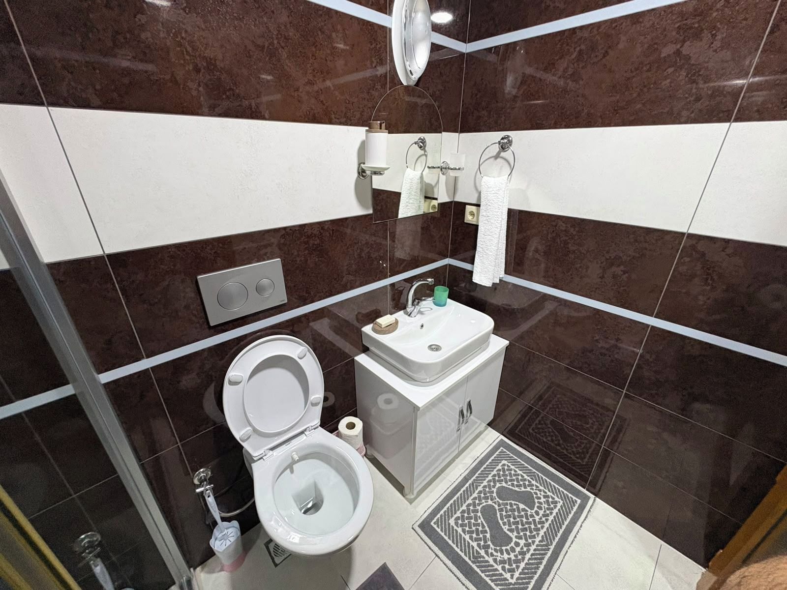 A modern bathroom with a toilet, sink, and shower.