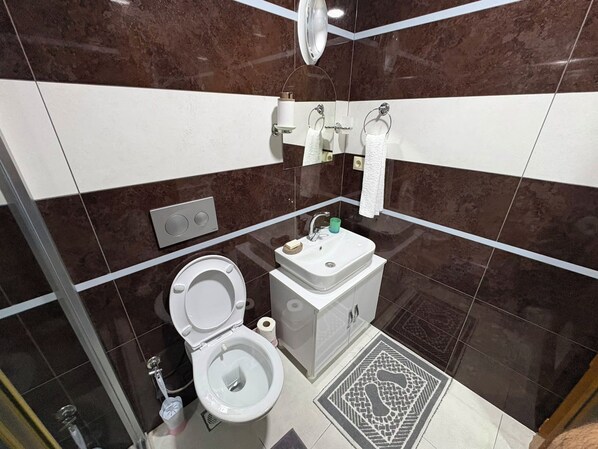 Un baño moderno con inodoro, lavabo y ducha.