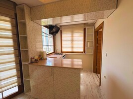 Una cocina compacta con estufa integrada, un lavamanos y una ventana con persianas.