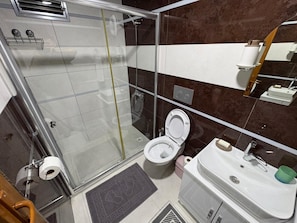 Eenvoudige kamer | Badkamer | Een douche, een haardroger, handdoeken, zeep