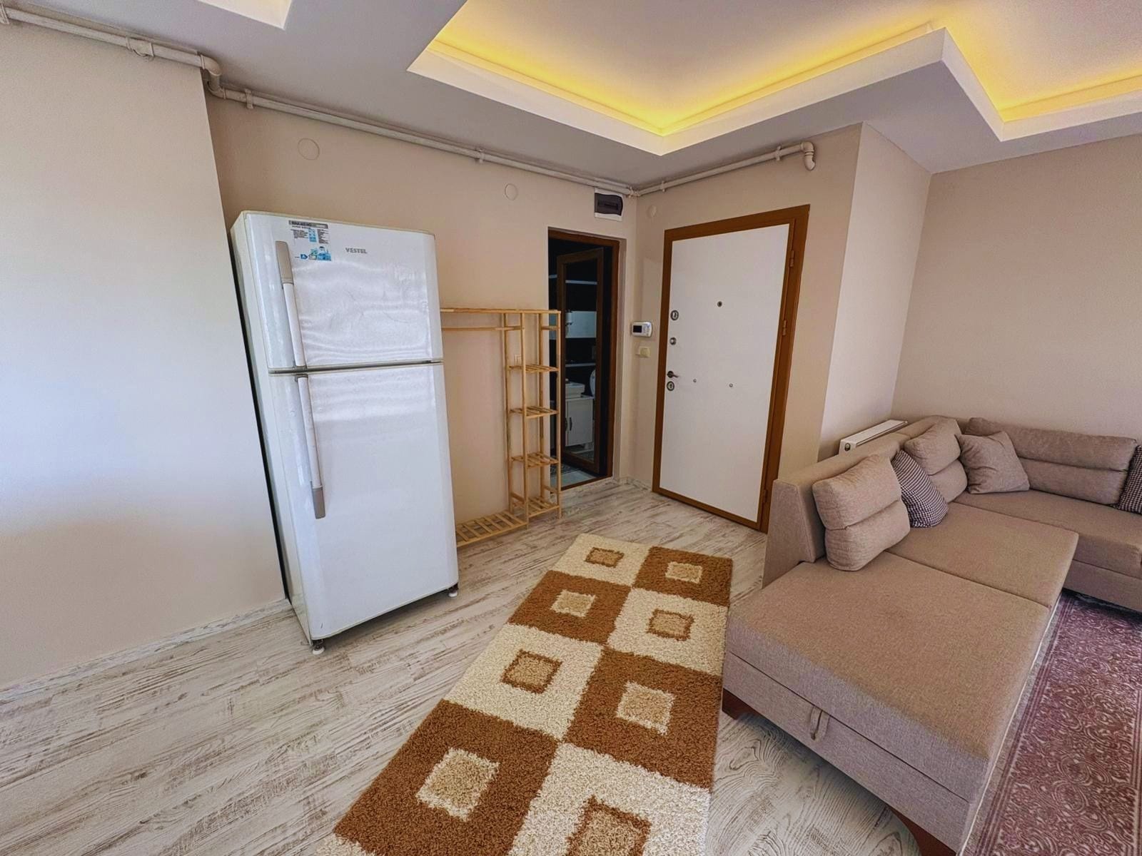 A compact living space with a kitchenette, a sofa, and a patterned rug.