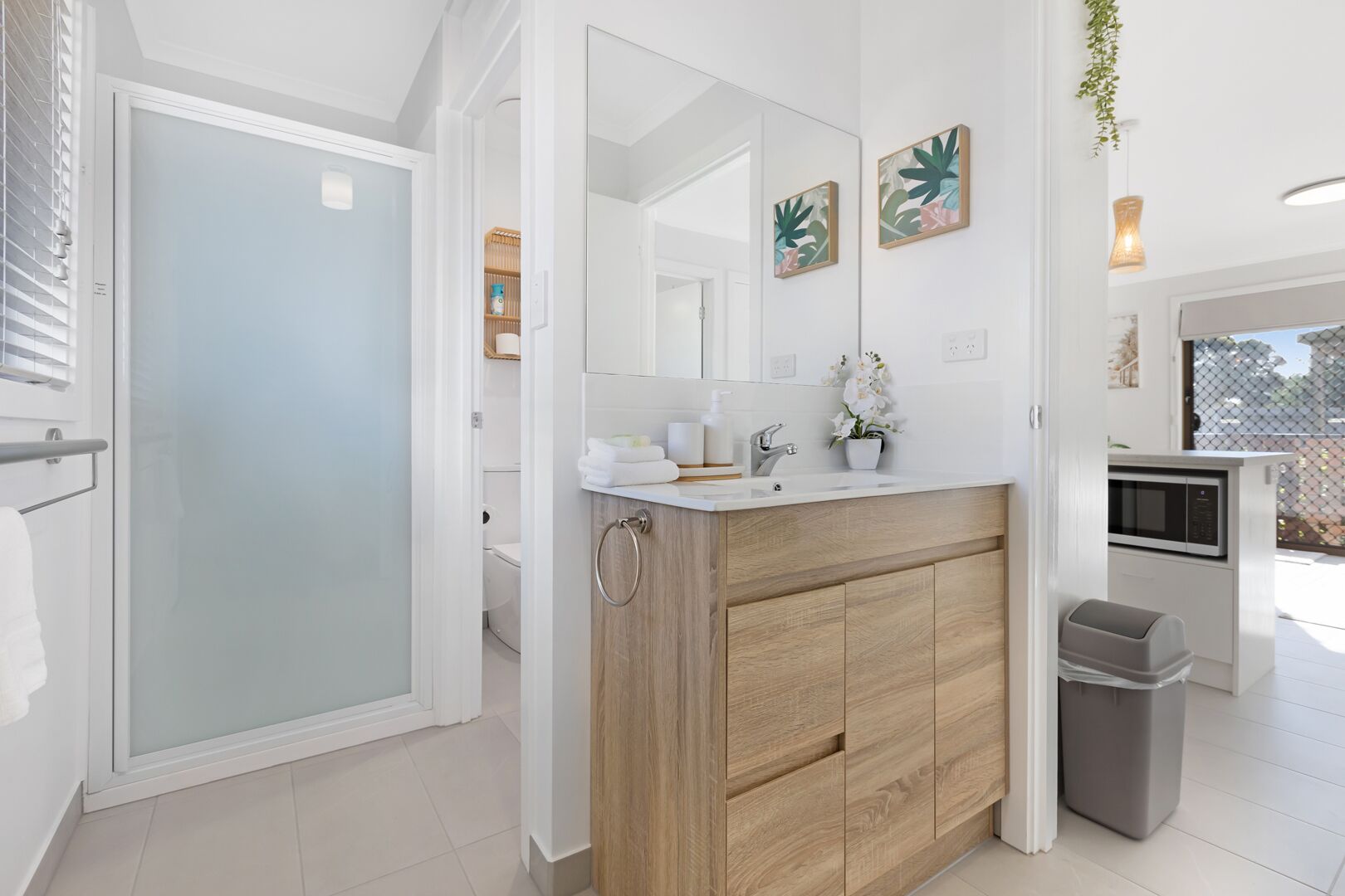 Un bagno moderno con box doccia in vetro, mobile lavabo in legno e uno specchio sopra.