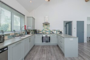 Eine moderne Küche mit Backofen, einer Kaffeemaschine und einem Fenster mit Jalousien.