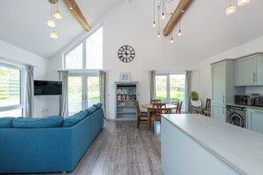A modern kitchen with a dining area, a sofa, and a large window. - Moranedd Bach (Holyhead)